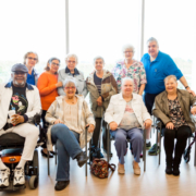 group of elderly people standing in a group smiling in a bright and sunny room comprehensive healthcare for elderly