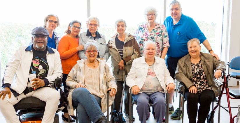group of elderly people standing in a group smiling in a bright and sunny room comprehensive healthcare for elderly